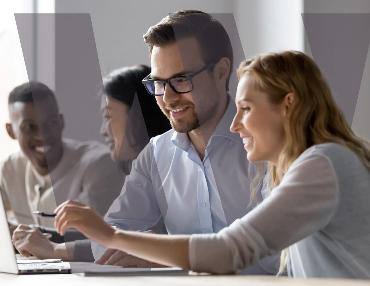 Smiling man and woman collaborating while looking at a tablet in a modern office setting.