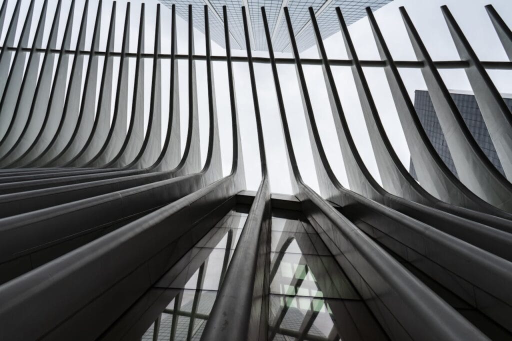 Upward view of modern architectural structure with curved steel beams and glass panels.