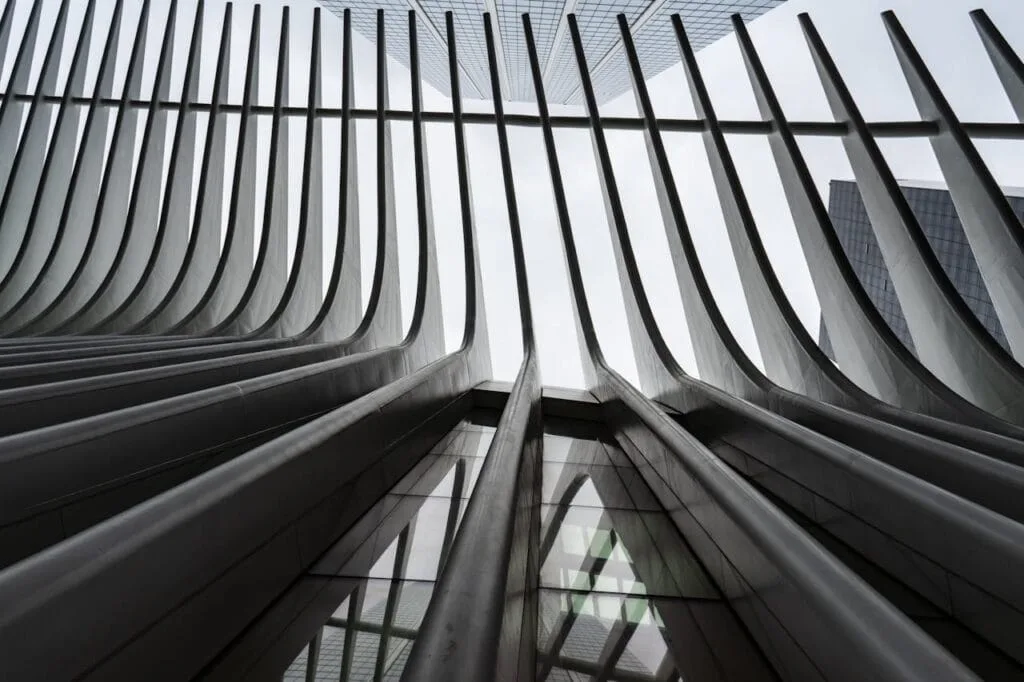 Upward view of modern architectural structure with curved steel beams and glass panels.