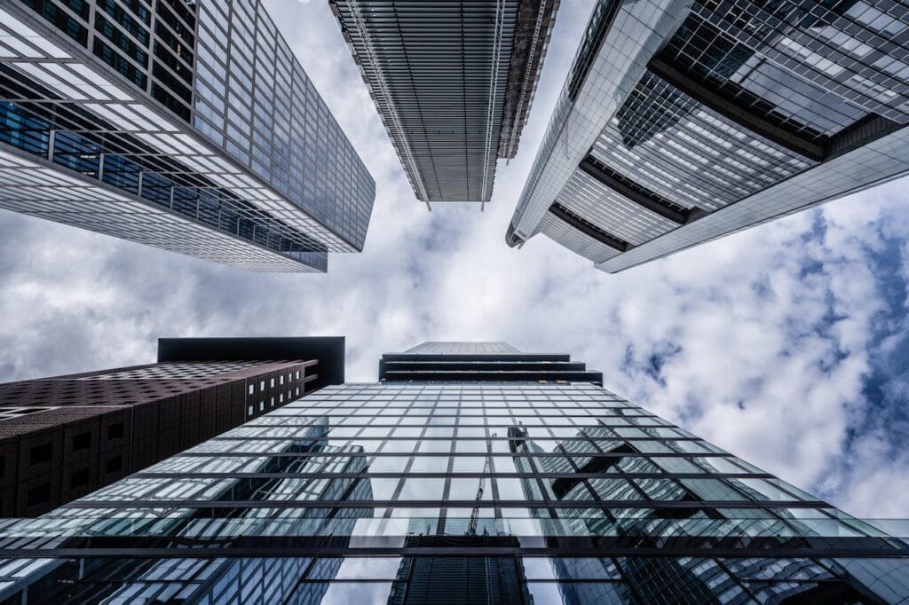 Upward view of modern skyscrapers with reflective glass facades against a partly cloudy sky.